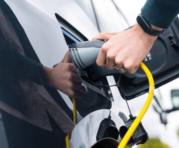 man-plugging-charger-into-electric-car-charge-station (1)-min